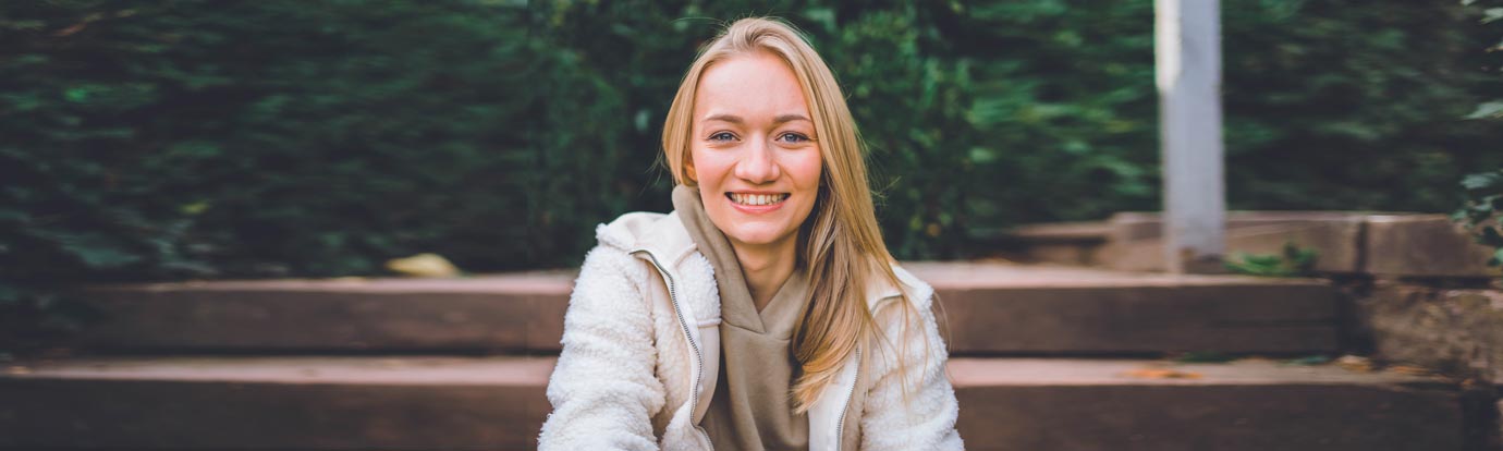 Emily Vontz sitzend auf der Treppe mit strahlendem Lächeln